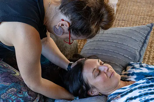 A breathwork facilitator guiding a woman through a session