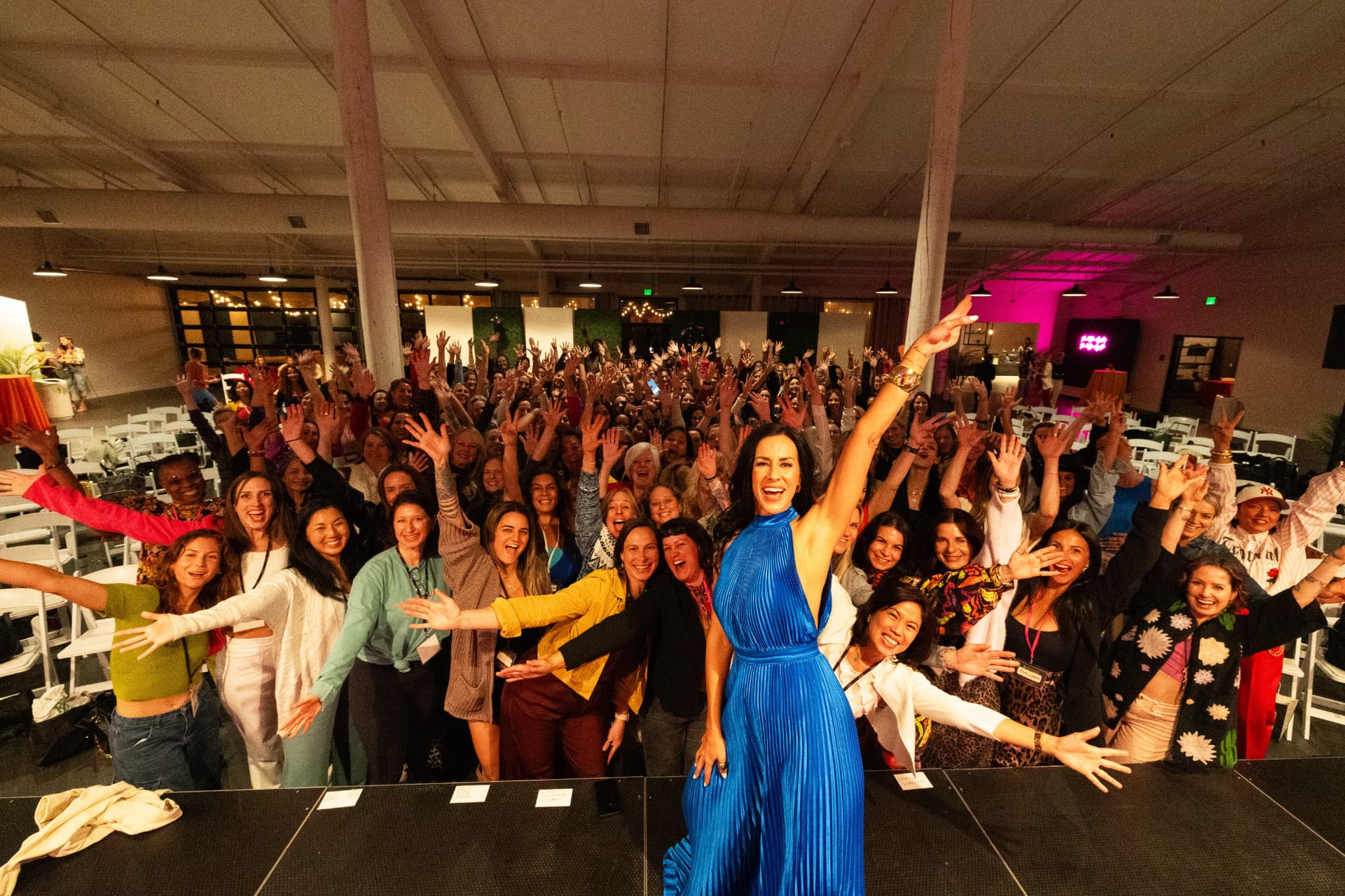 Samantha Skelly on stage with a joyful crowd of women at a Pause live event