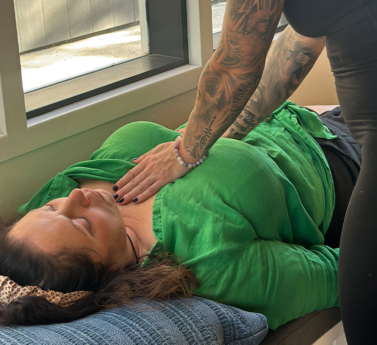 Facilitator placing a supportive hand on a client's chest during a somatic breathwork session